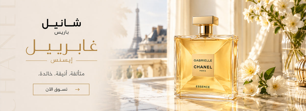 Chanel Gabrielle Essence perfume bottle beside white flowers, with the Eiffel Tower in the background and Arabic promotional text – perfumesouq qatar